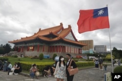 Orang-orang yang memakai masker berjalan di sekitar Chiang Kai-shek Memorial Hall di Taipei, Taiwan, pada 9 Oktober 2022. (Foto: AP)