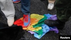 FILE - Anti-gay rights activists stand on a rainbow flag during an LGBT rally in central Moscow June 11, 2013.