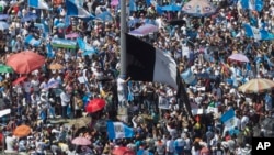 FILE - Protesters raise a black Guatemalan flag in Constitution Plaza as they demand the resignation of Guatemalan President Jimmy Morales in Guatemala City, Sept. 20, 2017. 