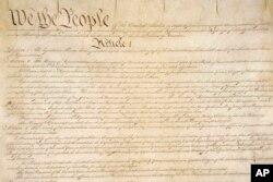 This photo made available by the U.S. National Archives shows a portion of the first page of the United States Constitution.