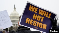 Seorang demonstran membawa poster berisi tulisan "Kami tidak akan mengundurkan diri" dalam aksi demo mendukung pegawai federal AS di depan Gedung Capitol, Washington, pada 11 Februari 2025. (Foto: Reuters/Craig Hudson)