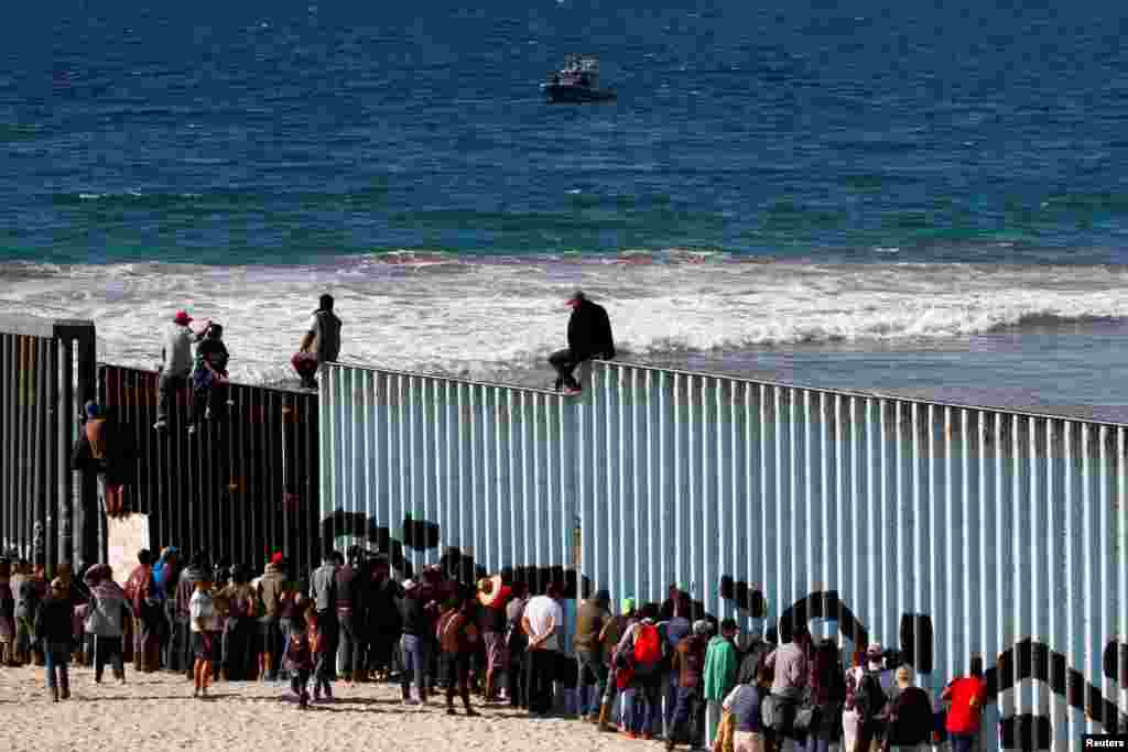 Migrants trying to reach the U.S. look through the border fence between Mexico and the United States, in Tijuana, Mexico, Nov. 14, 2018.