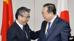 Japan's Deputy Minister of Foreign Affairs Shinsuke Sugiyama, left, and China's Assistant Foreign Minister Liu Jianchao shake hands before their meeting in Tokyo Thursday, March 19, 2015.