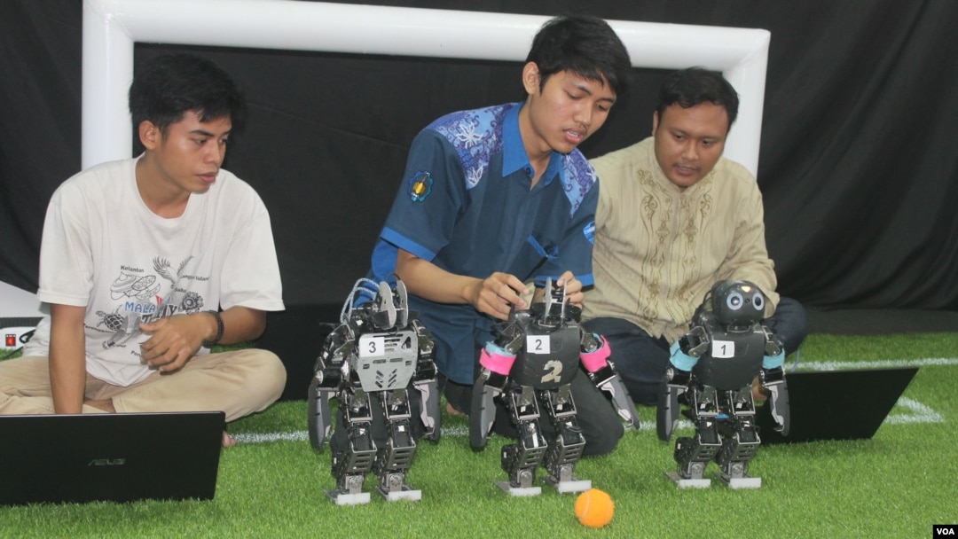 Mahasiswa ITS Surabaya mendemonstrasikan robot pemain sepak bola buatan tim robot ITS. (Foto: VOA/Petrus Riski).