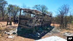 Emergency services stand near to a burned out bus after a bus accident in Gwanda about 550 kilometres south of the capital Harare, Nov. 16, 2018. Police in Zimbabwe say more than 40 people have been killed in a bus accident Thursday night.