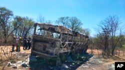 Emergency services stand near to a burned out bus after a bus accident in Gwanda about 550 kilometres south of the capital Harare, Nov. 16, 2018. Police in Zimbabwe say more than 40 people have been killed in a bus accident Thursday night.