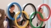 Gente posa para una foto con la exhibición de los Anillos Olímpicos en el Aeropuerto Internacional de Haneda en Tokio, el jueves 8 de julio de 2021. (AP Photo / Koji Sasahara)