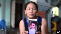 Hoang Thi Ai holds up her phone showing a photo of her son, Hoang Van Tiep, who she fears is one of the possible victims in the truck deaths in England, at her home in Dien Chau district, Nghe An province, Vietnam, Oct. 28, 2019.