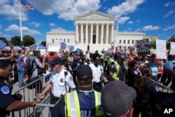 FILE - U.S. Supreme Court police officers and U.S. Capitol Police officers place barriers between anti-abortion-rights and abortion-rights demonstrators outside the Supreme Court, June 24, 2024, in Washington.