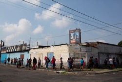 People stand in line to buy food from a small grocery store in the "La Reformita" neighborhood during a lockdown in Guatemala City, May 15, 2020.