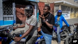 Jimmy Cherizier, the leader of the "G9 et Famille" gang, talks with members of his gang while taking a ride on the back of a motorcycle in his district of Delmas 6 in Port-au-Prince, Haiti, Jan. 24, 2023. 