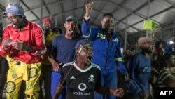 FILE - Mineworkers demonstrate outside the entrance to the Gold One Modder East operation mineshaft in Springs, on October 24, 2023.