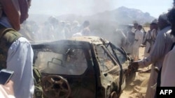 Yemenis gather around a burned car after it was targeted by a drone strike, which killed three suspected al-Qaida militants, between Marib and Chabwa provinces, a desert area east of Sana'a, Jan. 26, 2015.