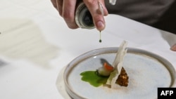 FILE - French chef Mathieu Gasnier serves puffed cassava chips, grilled okra placali at the Maison Palmer restaurant in Abidjan on October 30, 2023.