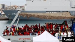 Des migrants attendent pour descendre du bateau de la Royal Navy Ship HMS Enterprise dans un port sicilien, Italie, le 23 octobre 2016.