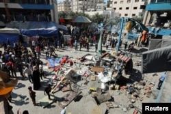 Warga Palestina berkumpul di lokasi serangan udara Israel di sebuah sekolah PBB yang menampung para pengungsi di Nusairat di Jalur Gaza tengah, 14 Juli 2024. (Foto: REUTERS/Ramadan Abed)