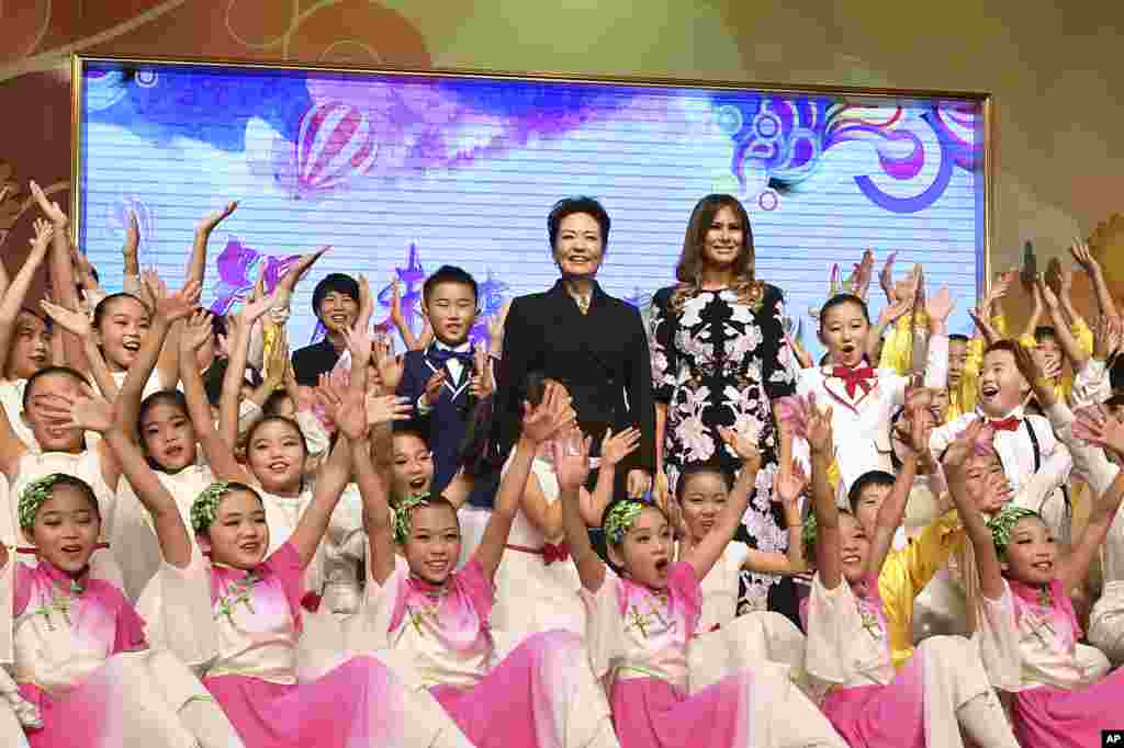 Primeira-dama dos EUA, Melania Trump, e primeira-dama da China Peng Liyuan, rodeadas por estudantes durante uma apresentação cultural, aquando da visita à escola primária Banchang Primary em Pequim, 9 de Novembro, 2017