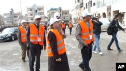 FILE - In this Jan. 3, 2012 file photo provided by the Syrian official news agency SANA, Arab League monitors walk through the Al-Sabil area of Daraa, Syria.