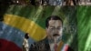 Un hombre con mascarilla pasa frente a un mural del presidente en disputa de Venezuela, Nicolás Maduro, en Caracas, Venezuela. Julio 22, 2020