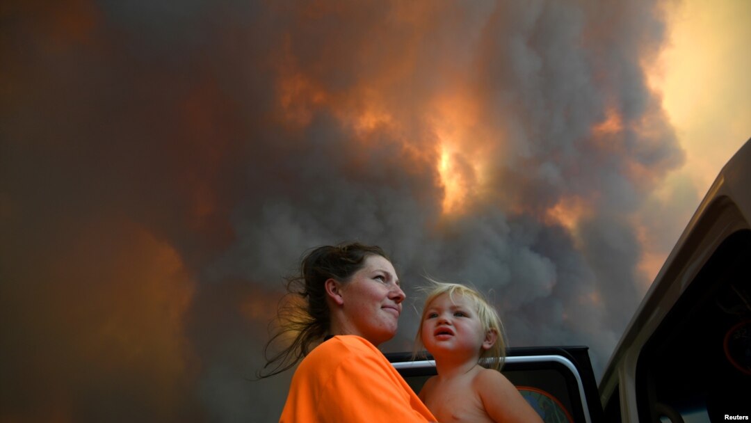 Sharnie Moren dan anaknya Charlotte memperhatikan kebakaran lahan dekat Nana Glen, Coffs Harbour, Australia, 12 November 2019.