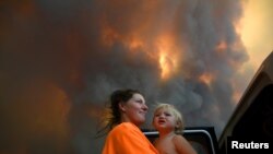 Sharnie Moren dan anaknya Charlotte memperhatikan kebakaran lahan dekat Nana Glen, Coffs Harbour, Australia, 12 November 2019.