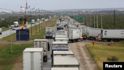 ARCHIVO - Camiones esperan en una larga fila para el control aduanero fronterizo para cruzar a EEUU en el Puente del Comercio Mundial en Nuevo Laredo, México, el 2 de noviembre de 2016. 