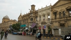 FILE - Motorcyclists drive on a road with old buildings in downtown Karachi, Pakistan, Aug. 29, 2024.