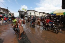 FILE - People and motorbikes pass along a junction at a market in the Waterside area of Monrovia, Oct. 13, 2011.