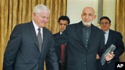 Defense Secretary Robert Gates (L) is escorted by Afghan President Hamid Karzai after a joint press conference at the presidential palace in Kabul, 08 Dec 2010