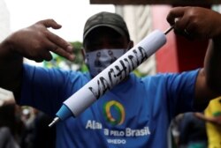 FILE - A man holds a mock syringe as demonstrators protest against Sao Paulo state governor Joao Doria and China's Sinovac COVID-19 vaccine, in Sao Paulo, Brazil, Nov. 1, 2020.