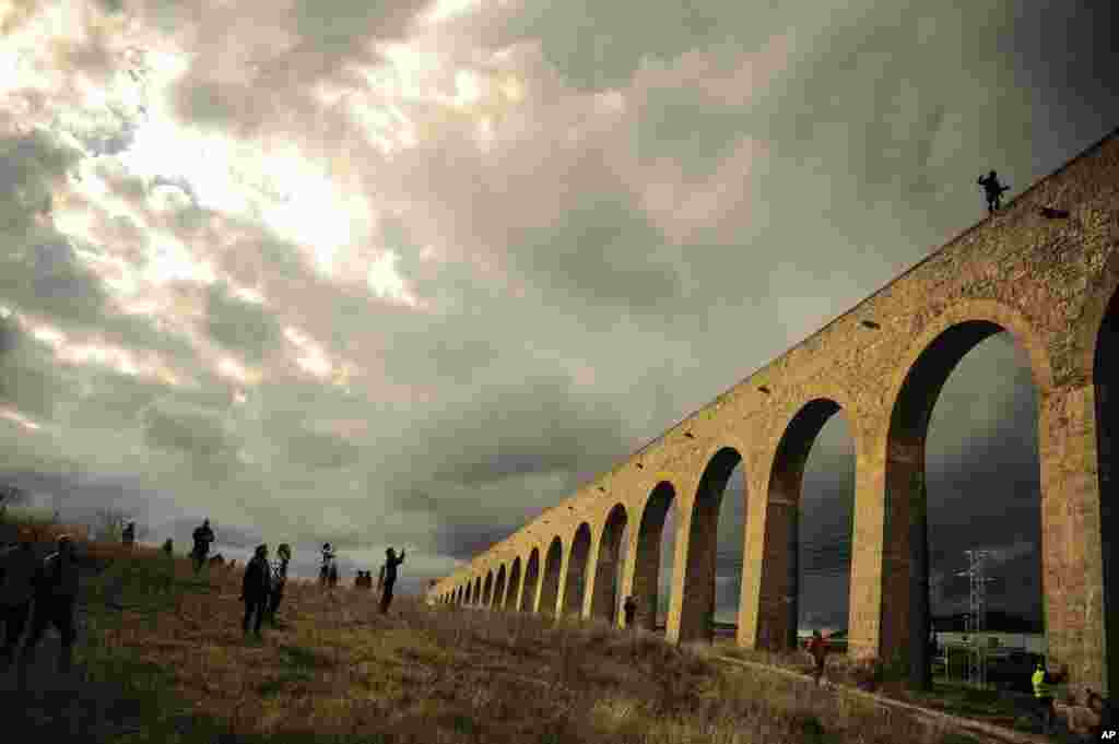 The Spanish illusionist named Peter III, top right, walks over an ancient aqueduct around 500 meters (0, 31 mile) with his head covered with a hood and his body wrapped in chains while people look on, in Noain, northern Spain. Pedro walked the half-mile in 52 minutes.