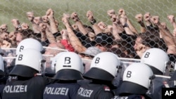 Austrian police stand behind a fence with when they practice the protection of the border between Slovenia and Austria in Spielfeld, Austria, Tuesday, June 26, 2018.