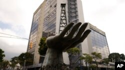 La escultura de una mano sosteniendo un pozo petrolero se exhibe al frente de una sede de la estatal PDVSA, en Caracas, el 21 de marzo de 2023.