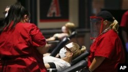 FILE - People donate blood during a Red Cross and Arizona Diamondbacks baseball team blood drive at Chase Field on April 28, 2020, in Phoenix, Arizona. Coronavirus concerns have caused blood donations to plunge.