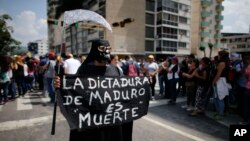 A woman dressed in a grim reaper costume holds a sign that reads in Spanish: "Maduro's dictatorship is death" during a rally in Caracas, Venezuela, April 27, 2017.