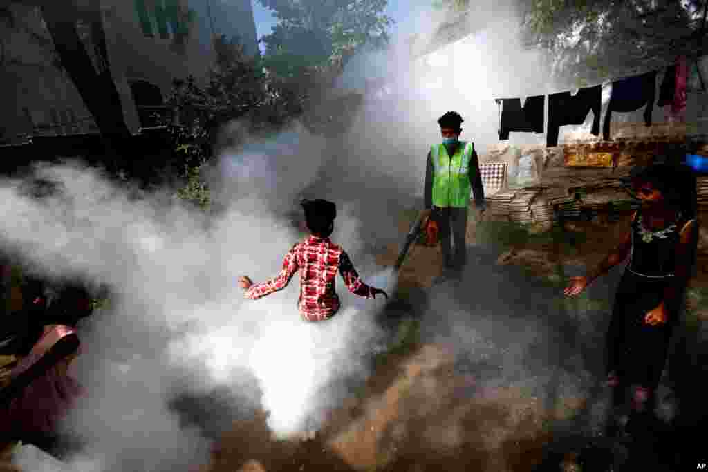 A boy plays in smoke from fumigation being carried out by a municipal worker at a residential area in Ahmedabad, India.