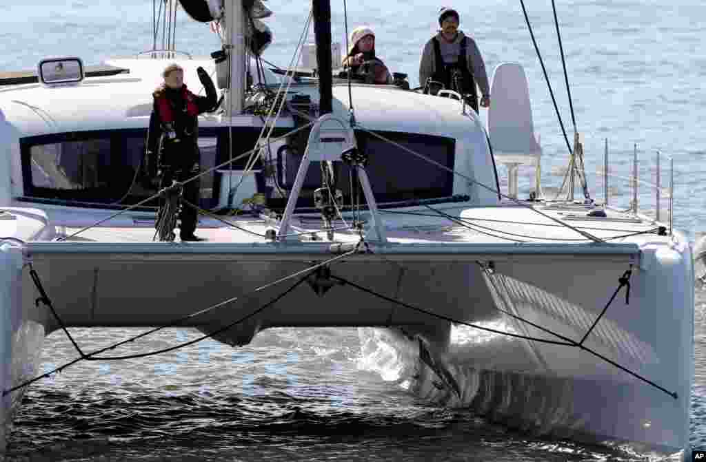 Climate activist Greta Thunberg waves as she arrives in Lisbon, Portugal, aboard the sailboat La Vagabonde.