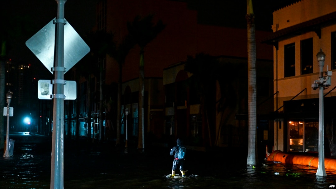 Un hombre toma fotografías y videos mientras camina por calles inundadas por las aguas después de que el huracán Milton tocó tierra en Fort Myers, Florida, el 9 de octubre de 2024.