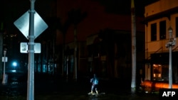 Un hombre toma fotografías y videos mientras camina por calles inundadas por las aguas después de que el huracán Milton tocó tierra en Fort Myers, Florida, el 9 de octubre de 2024.