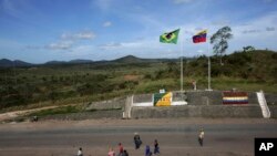 En esta foto de archivo de marzo de 2018, gente en la frontera entre Venezuela y Brasil cerca de la ciudad brasileña de Pacaraima, en el Estado Roraima. 