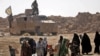 Civilians fleeing the battered Islamic State-held holdout of Baghuz walk past an armored vehicle belonging to the Manbij military council into a nearby area held by the Syrian Democratic Forces (SDF) in Syria, Feb. 12, 2019.