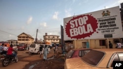 People pass a banner reading 'STOP EBOLA' forming part of Sierra Leone's Ebola free campaign in the city of Freetown, Sierra Leone, Jan. 15, 2016.