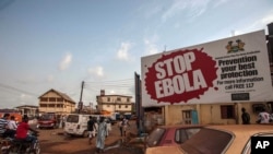 People pass a banner reading 'STOP EBOLA' forming part of Sierra Leone's Ebola free campaign in the city of Freetown, Sierra Leone, Jan. 15, 2016.