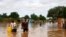 People, carrying their belongings, walk down a flooded street in the Kirkissoye neighborhood in Niamey, Niger, Aug. 27, 2020.