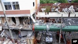 A Bangkok policeman stands outside the site of an overnight blast that left at least four people dead, 06 Oct 2010