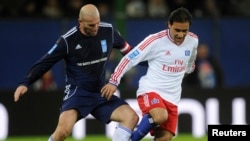 FILE - Zinedine Zidane of the Ronaldo, Zidane and Friends Team (L) challenges Mehdi Mahdavikia of the Hamburger SV Allstar Team during their "Match against Poverty" charity soccer match, in Hamburg Dec.13, 2011.