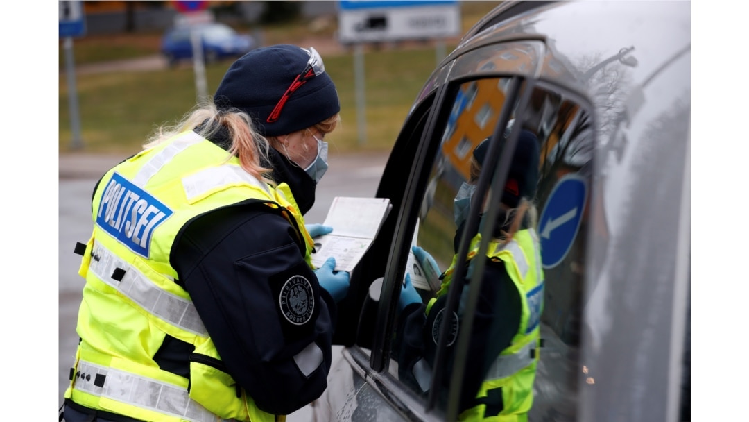 FILE - An Estonian police officer checks documents at the border crossing point as Estonia reintroduces border control and a ban to enter Estonia for foreigners as a preventive measure against the coronavirus in Valga, Estonia, March 17, 2020.
