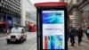 FILE - Pedestrians walk past a Huawei ad at a bus stop in central London, April 29, 2019.