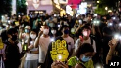 Orang-orang mengangkat telepon mereka dengan lampu menyala di distrik Causeway Bay di Hong Kong pada 4 Juni 2021, setelah polisi menutup tempat di mana orang-orang Hong Kong berkumpul setiap tahun untuk meratapi para korban Lapangan Tiananmen China. (Foto: AFP)