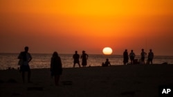 ARCHIVO: Personas observan el atardecer en una playa cerca del faro de Trafalgar, el 29 de julio de 2020, en Los Caños de Meca, España. 